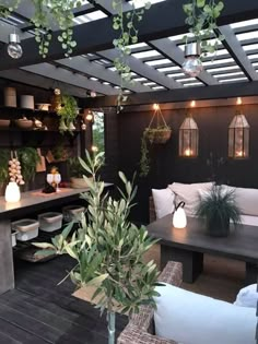 an outdoor living area with potted plants and lights on the ceiling, surrounded by wooden flooring