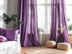 a living room with purple drapes and pillows on the floor, along with two planters