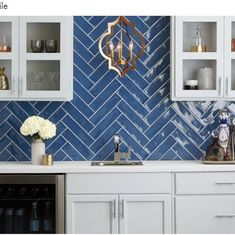 a kitchen with white cabinets and blue tile backsplashing on the back wall