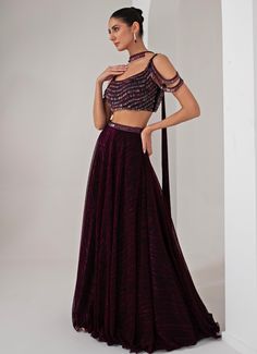 This stunning Black Platinoir Crepe Embellished Lehenga Set exudes modern elegance and glamour. Crafted from luxurious platinoir crepe, the black lehenga features a dramatic full-length skirt with all-over metallic brazen fall detailing, adding a shimmering effect with every movement. The crystal-embroidered waistband accentuates the waist, offering a refined silhouette. Teamed with a cold shoulder blouse, the ensemble reaches new heights with its halo crystal tassel embellishments, delivering a unique and stylish twist. The look is completed with a choker-style embellished dupatta, perfectly complementing the outfit with a sophisticated touch. Ideal for Cocktail parties, Sangeet nights, or evening events, this lehenga set is designed for those who wish to make a bold and fashionable state Embellished Lehenga, Black Lehenga, Embroidered Lehenga, Indian Wedding Wear, Full Length Skirts, Cocktail Parties, Choker Style, Cold Shoulder Blouse, Wedding Wear