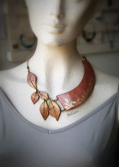 a white mannequin with a red and gold necklace on it's neck