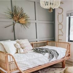 a day bed with pillows and a teddy bear on it next to a chandelier