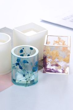 three candles sitting on top of a table next to each other with flowers in them