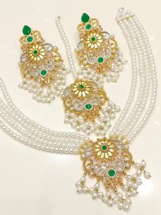 Add a touch of elegance and glamour to your attire with this stunning Shibra Mini Mala Zircon Necklace Set from My Jewel Box. The exquisite set includes a beautiful necklace, matching earrings and a Tikka that boast natural, multiple gemstones set in gold-coloured alloy. The jewellery set is perfect for special occasions like engagements, weddings, anniversaries, birthdays and Valentine's Day. The set's intricate design and excellent cut grade make it a must-have piece of Indian/Pakistani Bridal Elegant Silver Sets For Eid, Elegant Gold Sets For Reception, Elegant Green Sets For Reception, Elegant Stone Work Necklaces For Eid, Elegant Kundan Necklace With Zari Work For Reception, Elegant Stone Work Necklace For Eid, Elegant Bridal Necklace With Zari Work In Chandbali Shape, Elegant Bridal Necklace With Chandbali Zari Work, Elegant Bridal Necklace With Zari Work In Chandbali Style