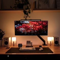 a flat screen tv sitting on top of a desk next to speakers and a keyboard