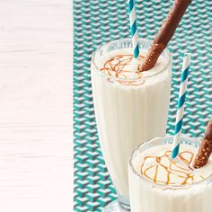 two glasses filled with milkshakes sitting on top of a blue and white table