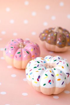 three donuts with sprinkles are stacked on top of each other in front of a pink background