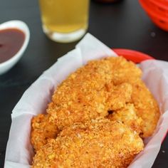 two fried chicken sticks in a basket with ketchup and sauce on the side