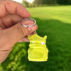 a hand holding a keychain with a small yellow animal on it's side