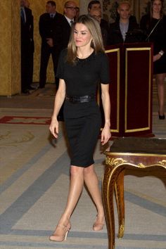 a woman in a black dress standing next to a table