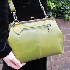 a woman holding a green purse in her hand