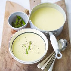 two bowls of soup are sitting on a cutting board