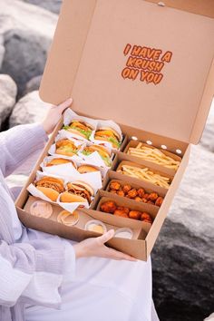 a woman is holding a box full of food