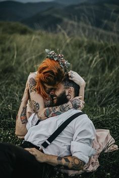 a tattooed couple cuddling in the grass