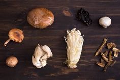 various mushrooms are arranged on a wooden surface