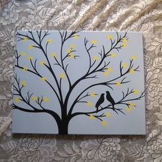 two birds sitting on a tree with yellow leaves painted on the canvas in front of them