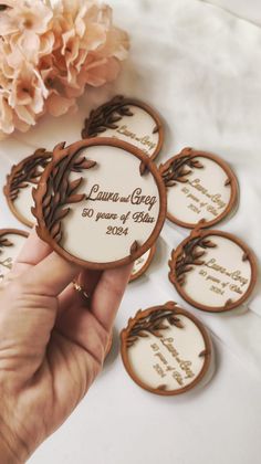 a person holding up some cookies with wedding date printed on the front and back side