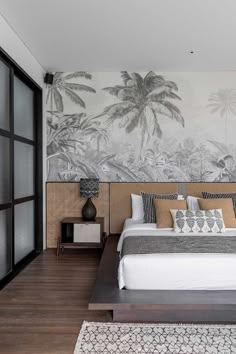 a bedroom with a large bed and palm trees painted on the wall behind it,