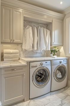 a washer and dryer in a white laundry room with lots of cabinet space