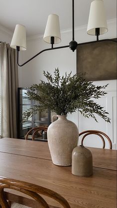 a large vase sitting on top of a wooden table next to a light fixture over a dining room table