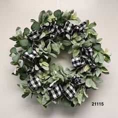 a wreath hanging on the side of a wall next to a white door with a black and white checkered ribbon