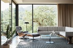 a living room with a couch, chair and coffee table in front of large windows