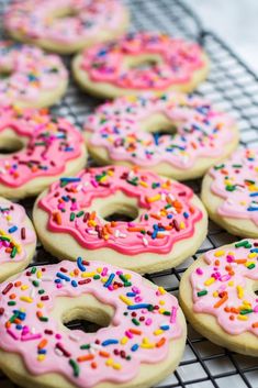 there are many donuts with pink frosting and sprinkles on the cooling rack