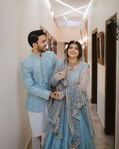 a man and woman dressed in blue standing next to each other on a long hallway