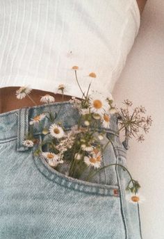 a woman's stomach with daisies in her jeans