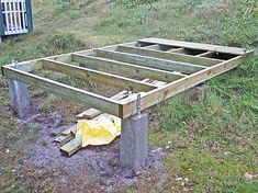 an unfinished wooden bench sitting on top of a lush green field