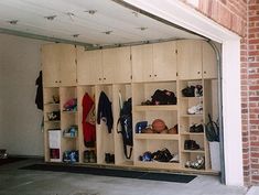 the inside of a garage with lots of shoes and coats hanging on wooden shelves next to a brick wall