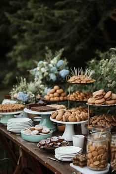 a table filled with lots of desserts and cookies on top of each other in front of trees