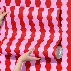 a woman's hand reaching for a red and white wallpaper with wavy lines