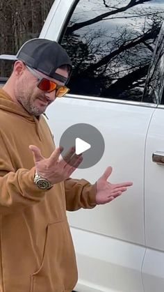 a man standing in front of a white car holding his hands out to the side