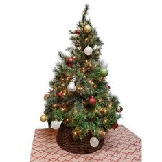 a small christmas tree in a basket with ornaments on the top and around it's base