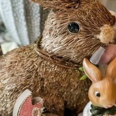 a close up of a stuffed animal with an egg in it's mouth and another toy rabbit next to it