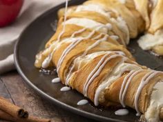 a croissant with white icing on a black plate