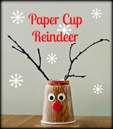 a paper cup reindeer made with branches and fake snowflakes on the side that says paper cup reindeer