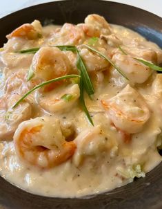 a bowl filled with shrimp and grits covered in gravy on top of a table