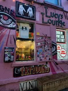 a pink building with lots of stickers on it's windows and signs above the window