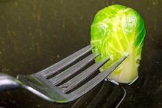 a piece of lettuce is being held by a fork with cheese on it