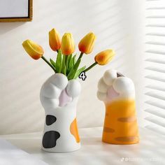 two vases with flowers in them sitting on a table