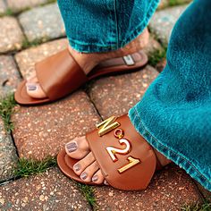 Description: Brown leather slides with a gold-tone metal logo plaque on one top strap Slip on, round open toe Small stacked heel Details: Upper: 100% calf leather Lining: 100% goat leather Sole: 100% rubber Branded leather insole Fit: True to size Care for Logo Slide: Gently wipe clean with a damp cloth When wet, allow to dry naturally; avoid artificial heat Flat Gladiator Sandals, Stylish Summer Outfits, Chic Sandals, Trending Sandals, Faux Leather Heels, Satin Pumps, Classic Pumps, Barefoot Shoes, Cute Sandals