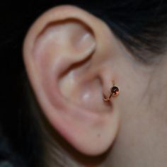 a woman's ear is shown with an orange stone in it