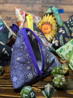 several dice bags with different designs and numbers on them sitting on a wooden table next to other dice pieces