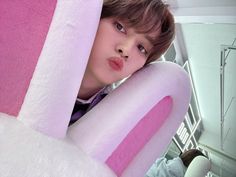 a young boy is peeking out from behind a large stuffed animal that looks like a bunny