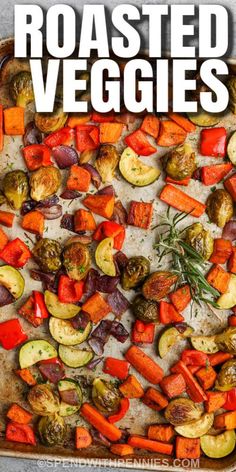 roasted veggies on a baking sheet with rosemary garnish in the middle