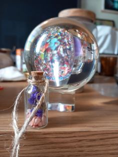 a glass bottle filled with colorful confetti on top of a wooden table next to a string