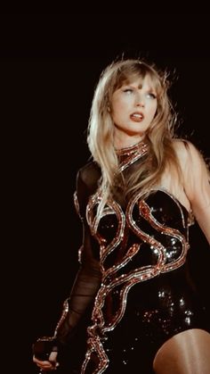 a woman in a black and gold outfit with her hands on her hips, posing for the camera