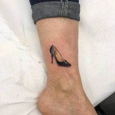 a woman's foot with a small shoe tattoo on the left side of her leg